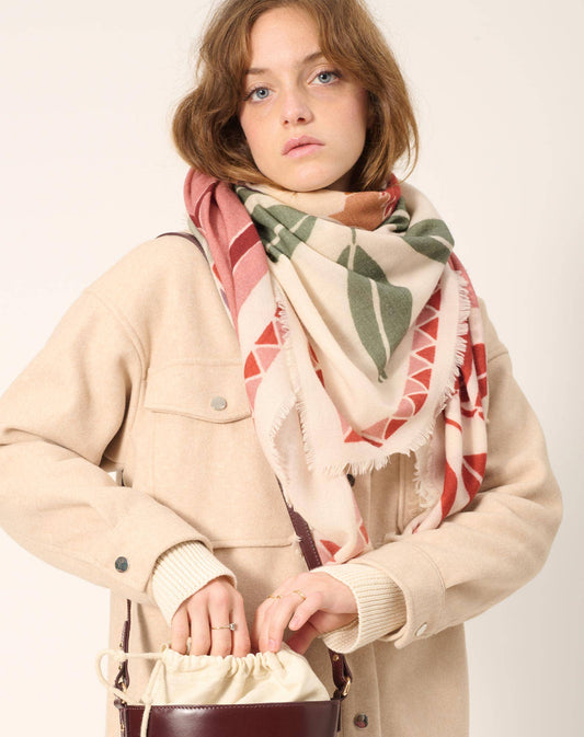 Women’s scarf from the French fashion brand Maradji. Tropical leaves and a parrot in shades terracotta, sage and caramel on a oat milk coloured background. Square shape, made from a sustainable wool and silk blend.