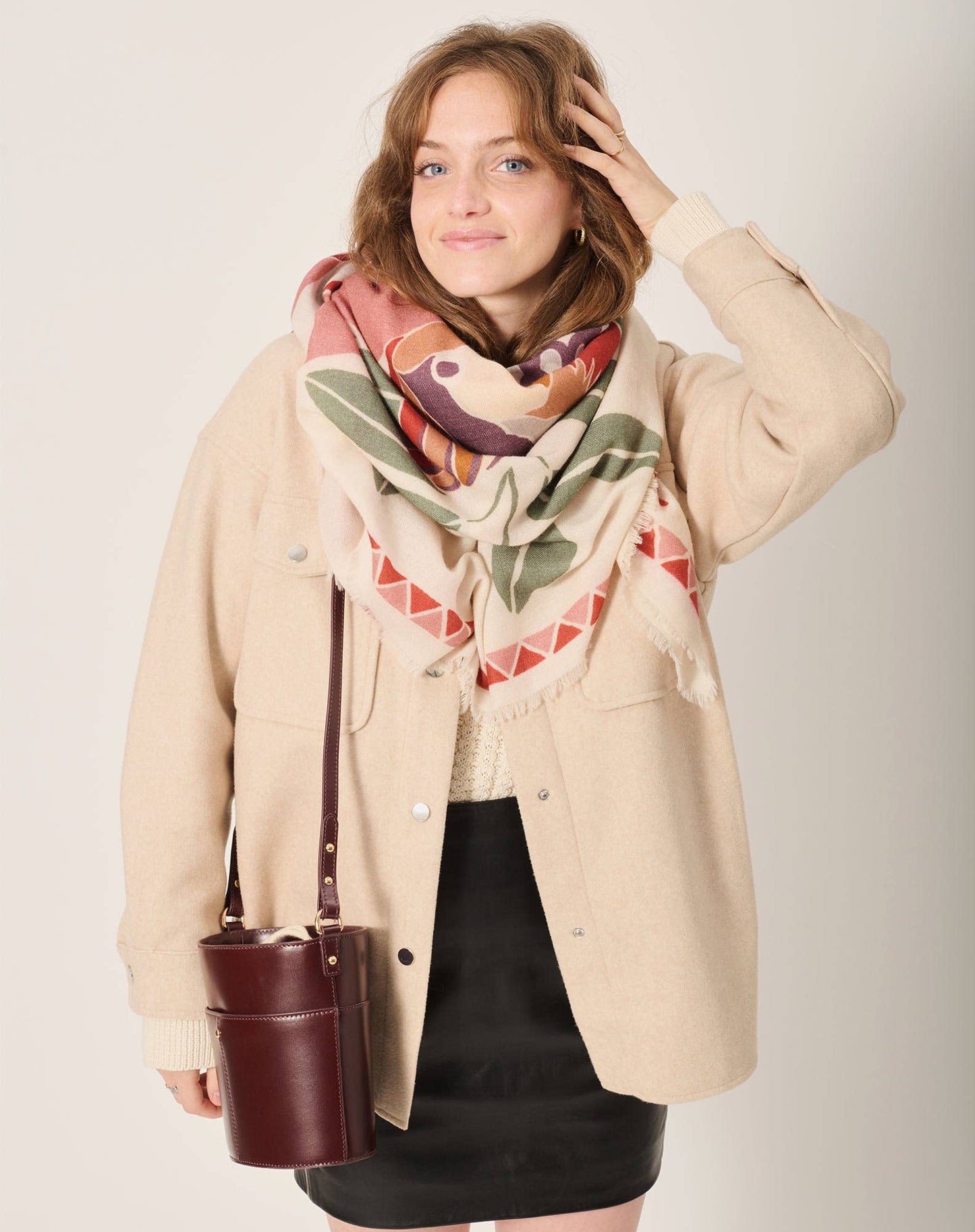 Women’s scarf from the French fashion brand Maradji. Tropical leaves and a parrot in shades terracotta, sage and caramel on a oat milk coloured background. Square shape, made from a sustainable wool and silk blend.