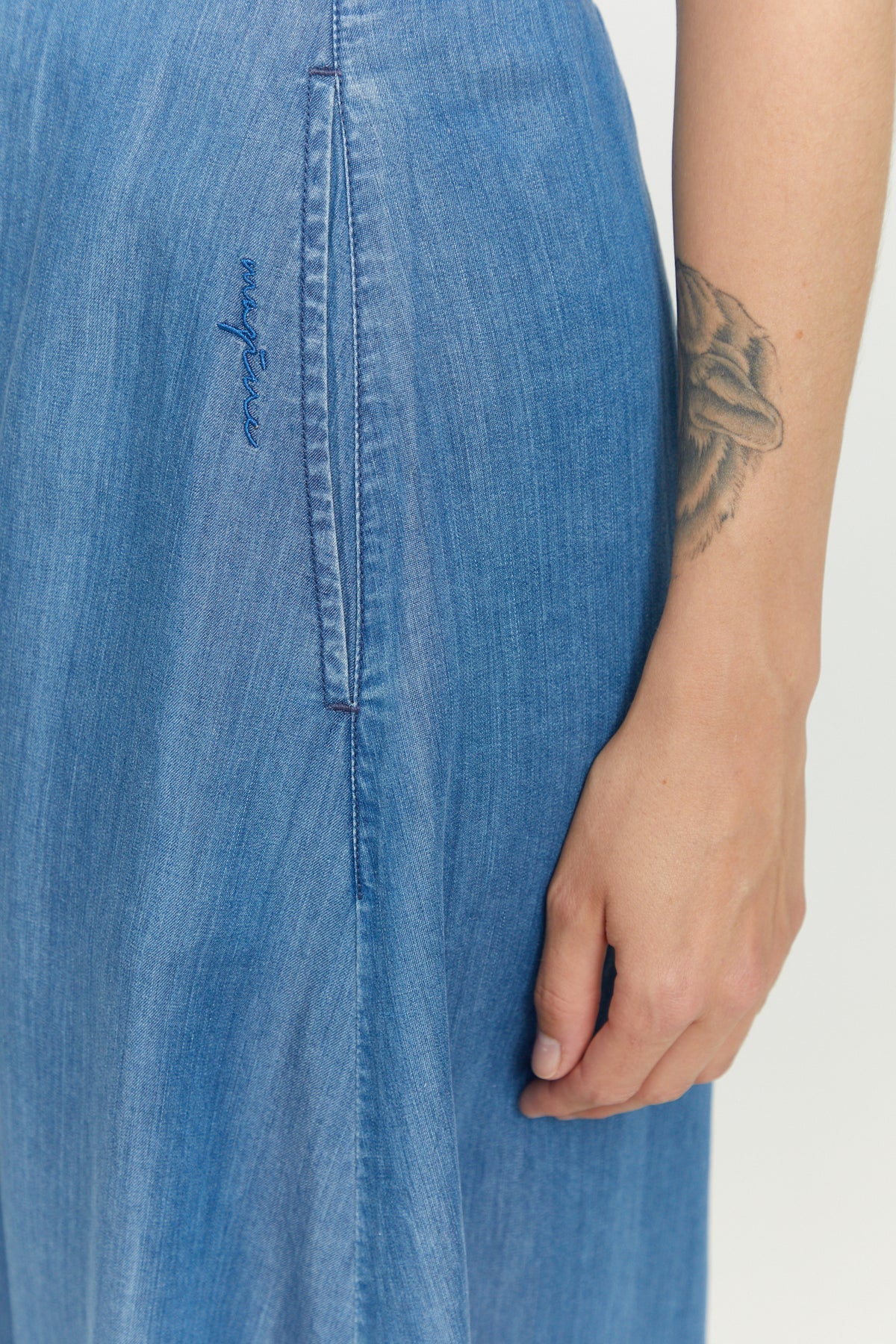 A-shape midi skirt in a mid denim wash, with a button placket down the front, an elasticated wIst and side pockets, made from sustainable Tencel™, by the German eco fashion brand Mazine.