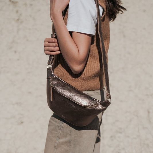 Woman carrying the Ann Kurz Leather Bum Bag in Metallic Rame