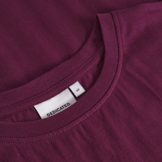 Close-up of a maroon t-shirt with a brand label on the collar.