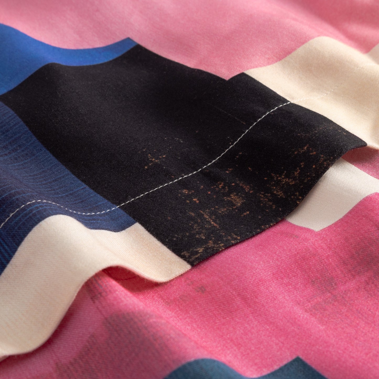 Close-up of a flag with red, white, and blue stripes and a black rectangular patch.