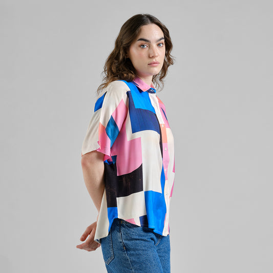 Woman wearing a colorful geometric patterned shirt on a gray background