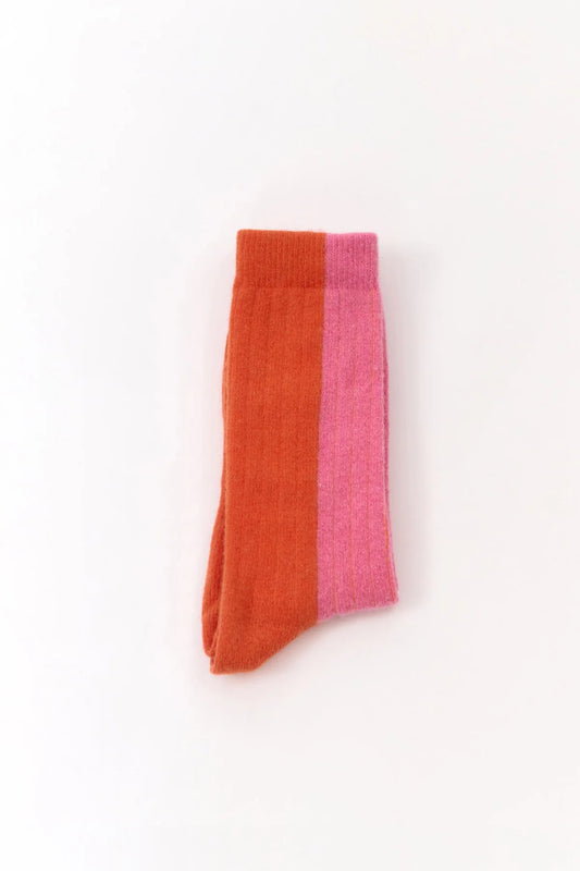 Colourful wool blend socks from the Spanish brand Suite13Lab. Made from 70% merino wool, 27% polyamide, 3% elastomer. With a pink front and top side of the foot and an orange back and heel. Made in Spain.