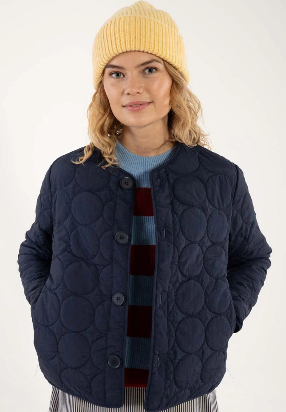 Daneland quilted jacket from Danefae Copenhagen in classic navy. Perfect as a thermo layer underneath a coat or worn by itself as a transitional jacket. Round neck, long sleeves and button closure with four buttons in the same colour as the jacket. Roomy side pockets. Round hem. Made from 100% nylon. Water repellent in light showers.