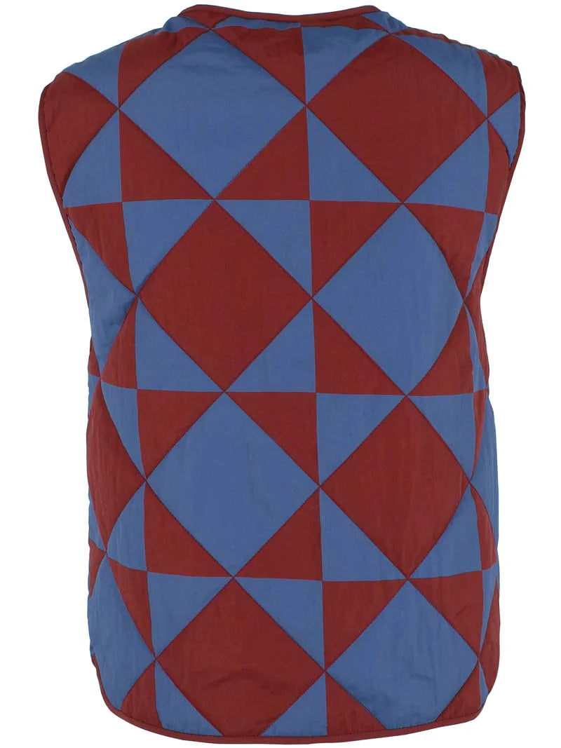 Quilted thermo gilet from Danefae Copenhagen. Regular length, round neck, button closure with four buttons, roomy patch pockets. Featuring a geometric pattern of diametrically placed squares and triangles in brick red and denim blue. Made from nylon.