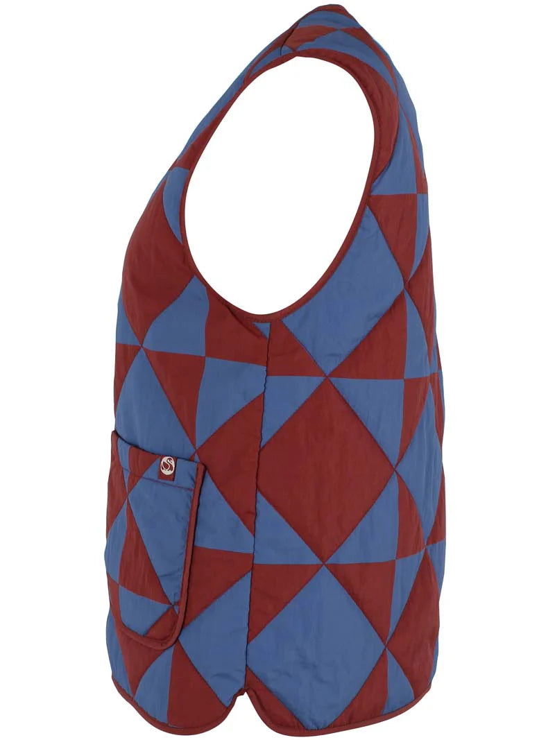 Quilted thermo gilet from Danefae Copenhagen. Regular length, round neck, button closure with four buttons, roomy patch pockets. Featuring a geometric pattern of diametrically placed squares and triangles in brick red and denim blue. Made from nylon.