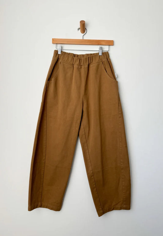 Arc Pants by Le Bon Shoppe. Barrel leg trousers made from cotton canvas, with deep side pockets and an elastic waistband. The colour is tobacco.