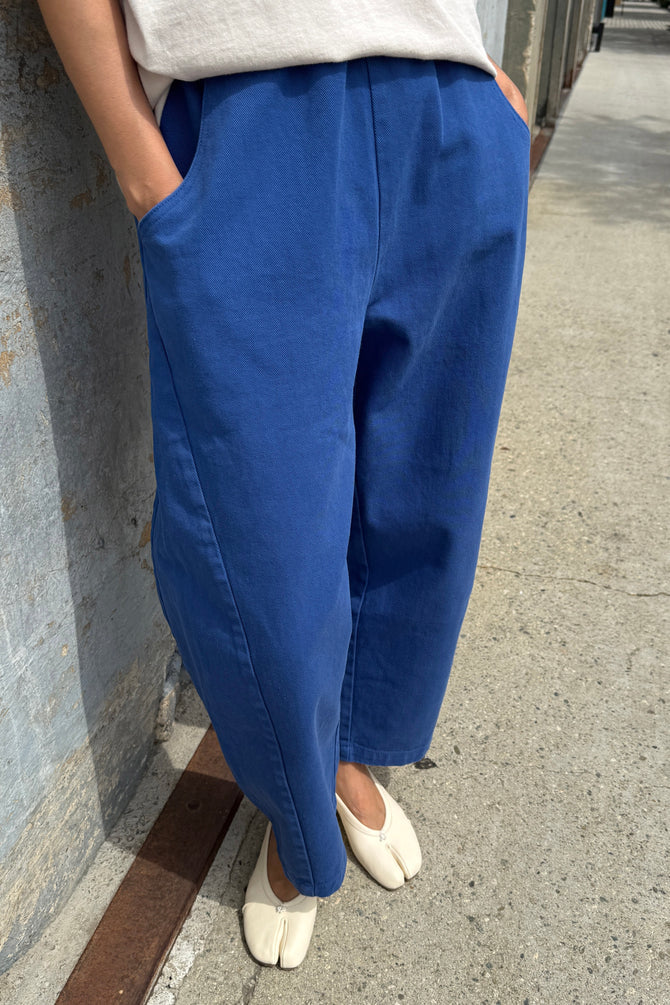 Person wearing azure blue Arc pants by Le Bon Shoppe and white shoes on a sidewalk.
