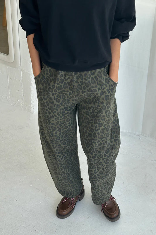 Arc Pants from Le Bon Shoppe. Barrel leg trousers made from durable cotton canvas. Featuring an elastic high waist, deep side pockets, and a slightly curved, cropped leg with a unique side panel. Leopard print on dark green background.