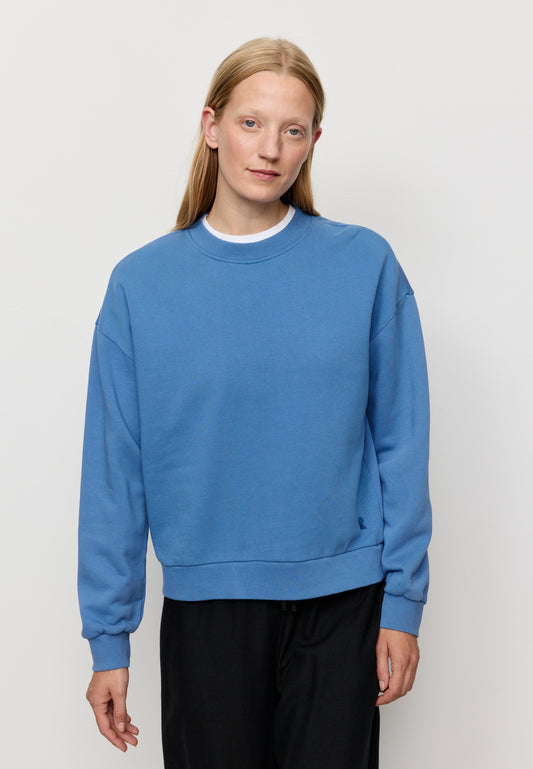 Woman wearing a blue sweatshirt against a plain background