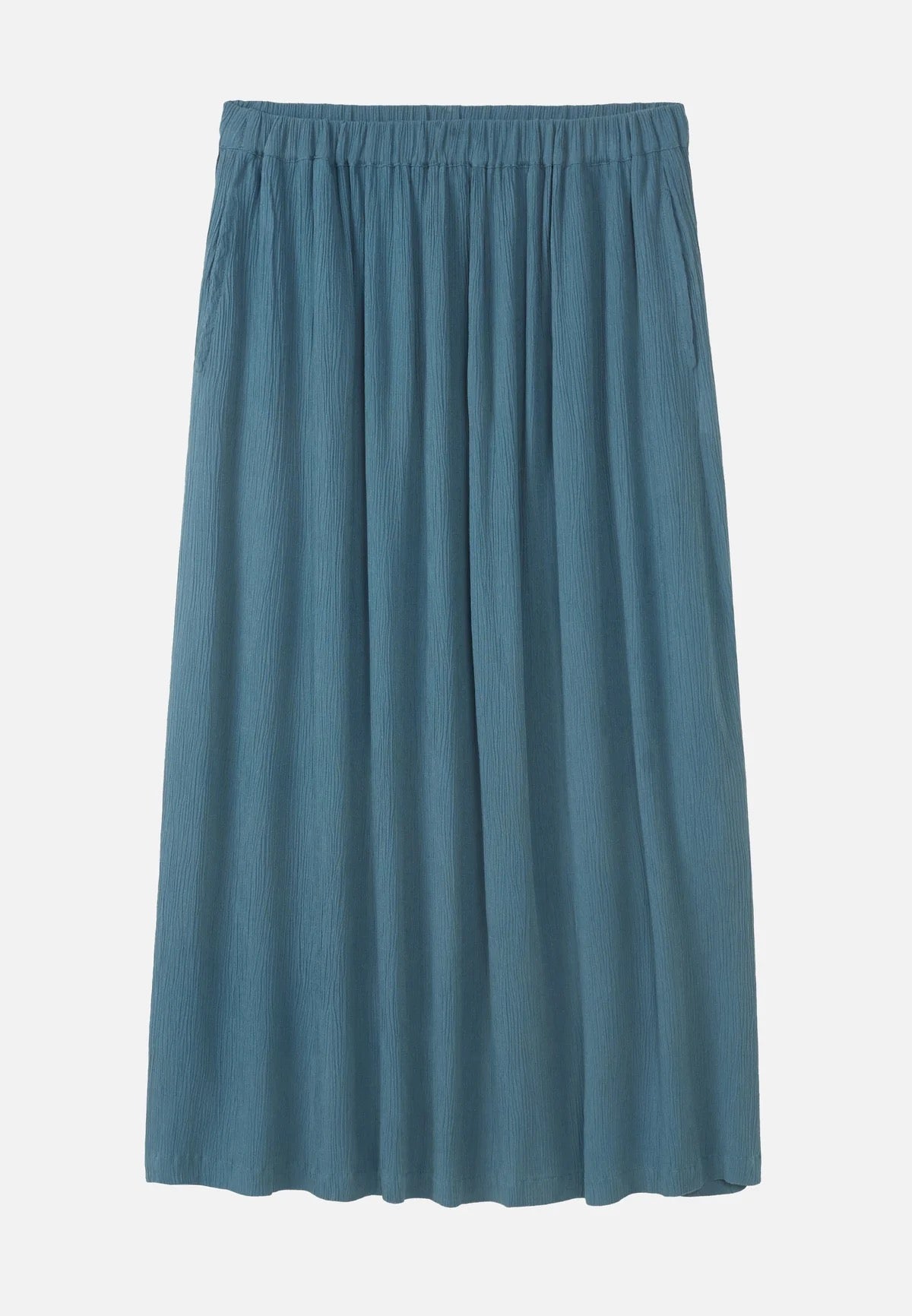 A rich teal LENZING™ ECOVERO™ midi skirt from Recolution is shown, featuring a high-waisted, elastic waistband with a gathered design and a subtle front slit. The skirt has a soft, crinkled texture and flows gracefully, with side pockets adding functionality. It is displayed against a plain light gray background, highlighting its full silhouette from the back.