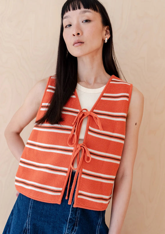 Knitted sleeveless vest from TBCo in a bold orange, with fine horizontal stripes in cream and dark brown. Made from 100% high-quality cotton. With two front ties for adjustable styling.