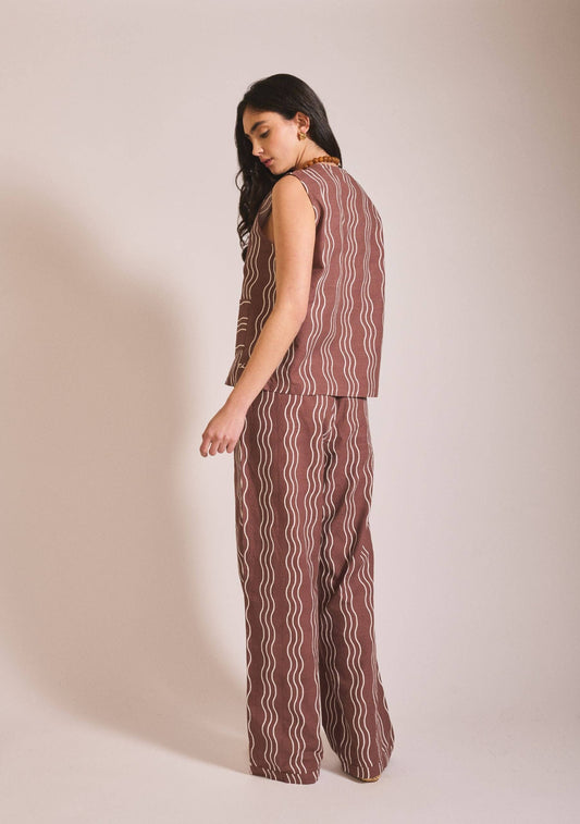 Woman wearing a brown patterned outfit on a beige background