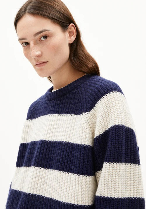 Woman wearing a navy blue and white striped chunky knit jumper made from organic cotton and organic wool, on a white background