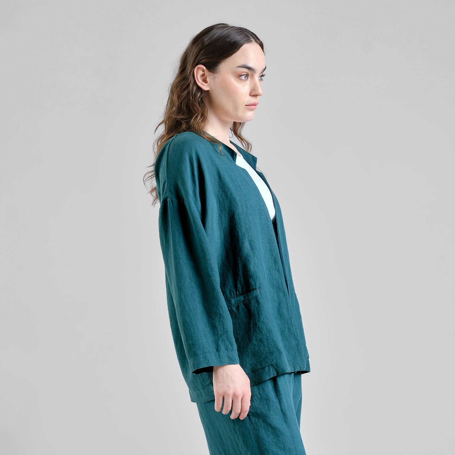 Woman wearing a teal linen outfit against a gray background