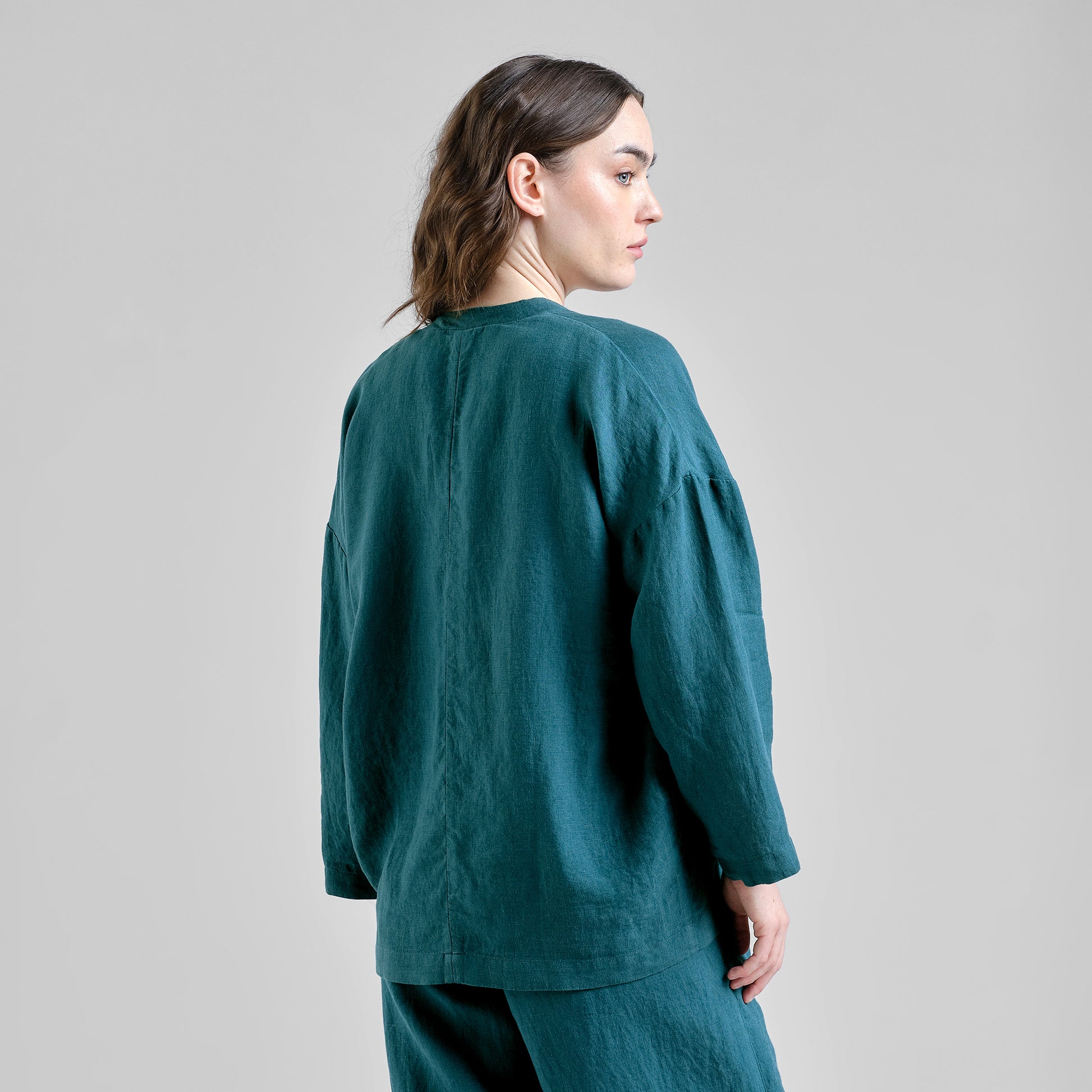 Person wearing a teal linen outfit on a plain background