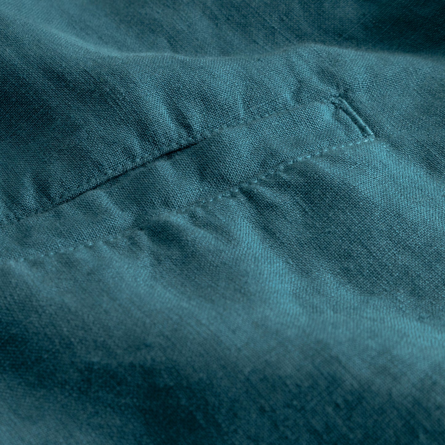 Close-up of teal linen fabric with stitching details