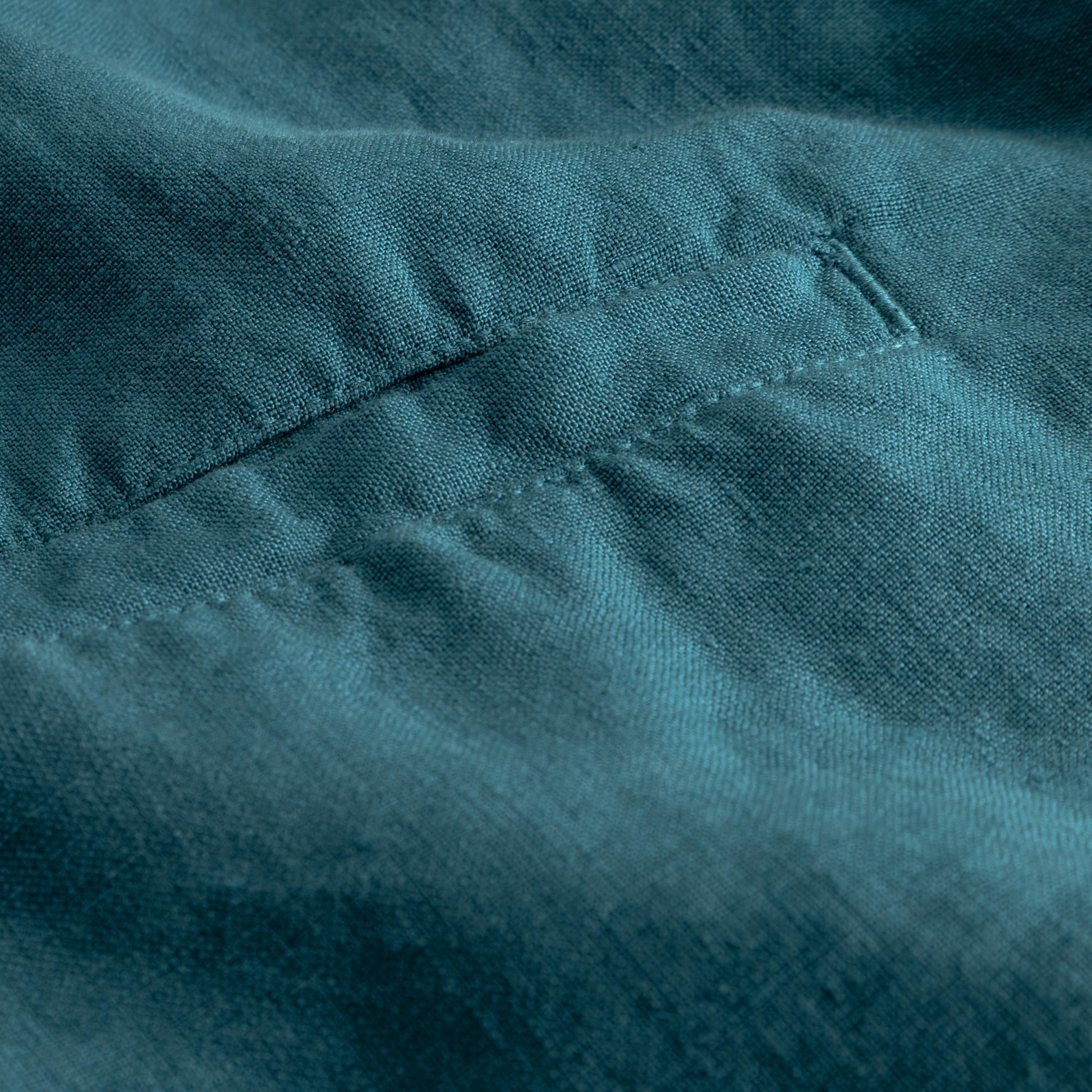 Close-up of teal linen fabric with stitching details