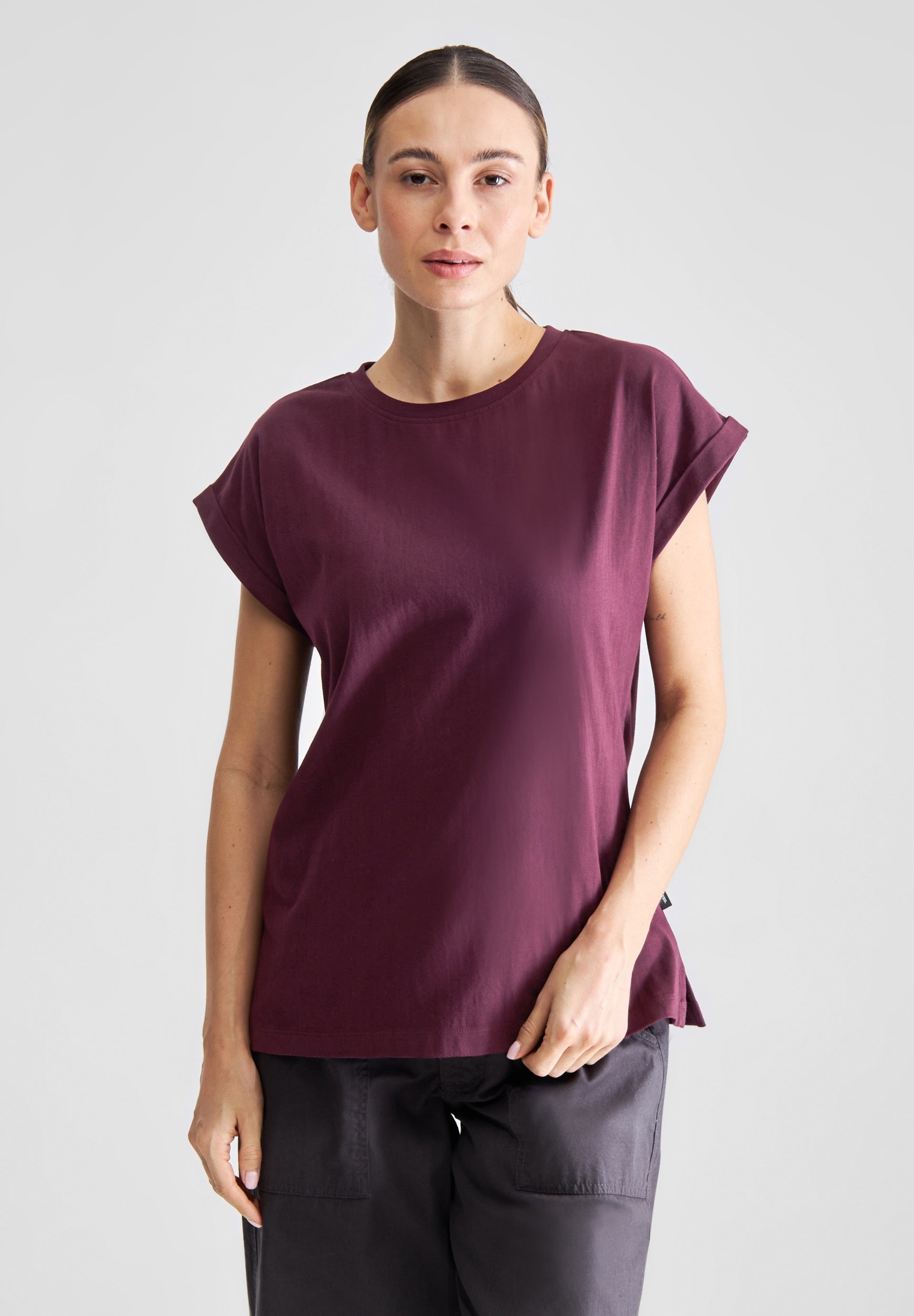 Woman wearing a burgundy t-shirt against a plain background