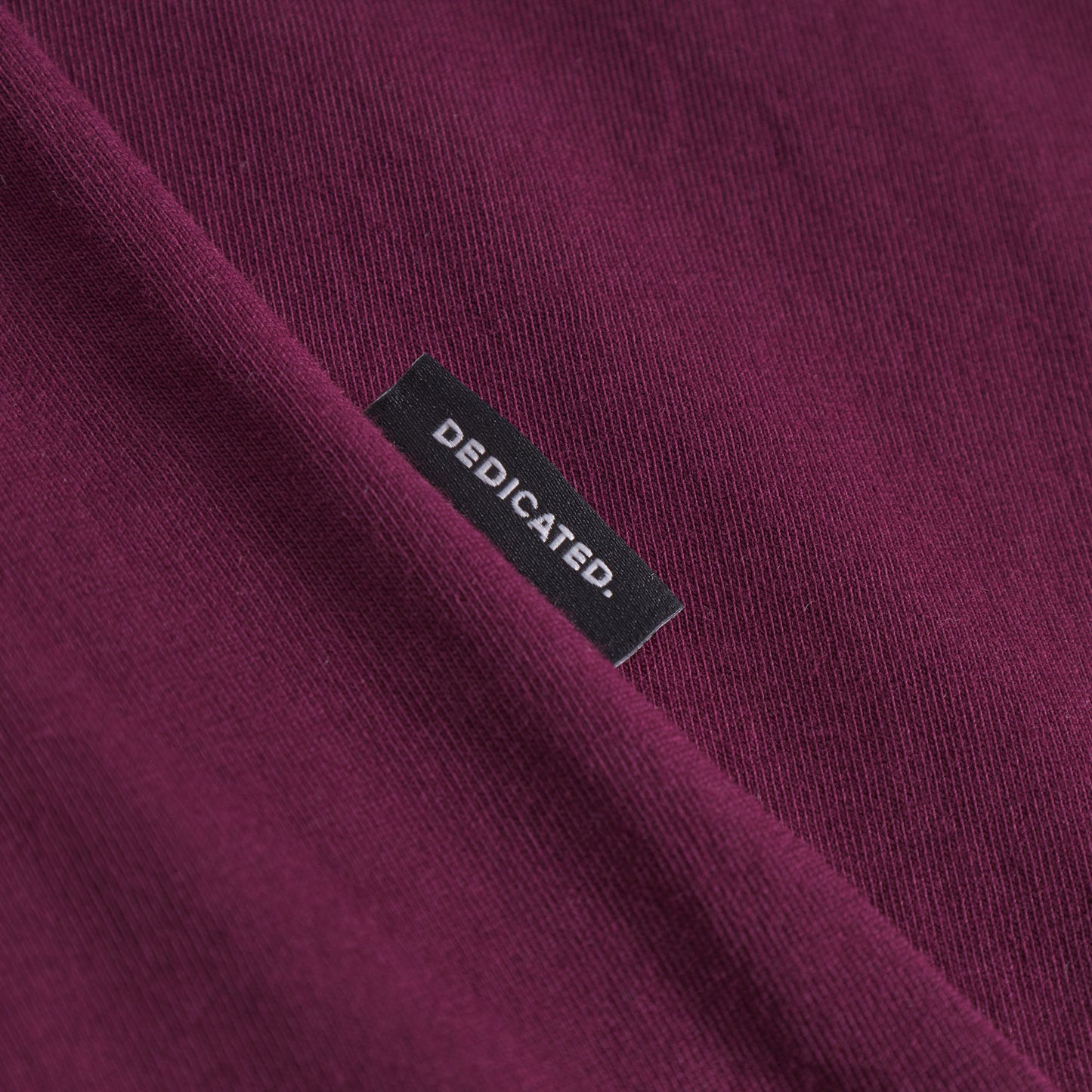 Close-up of a purple garment with a 'Dedicated' label.