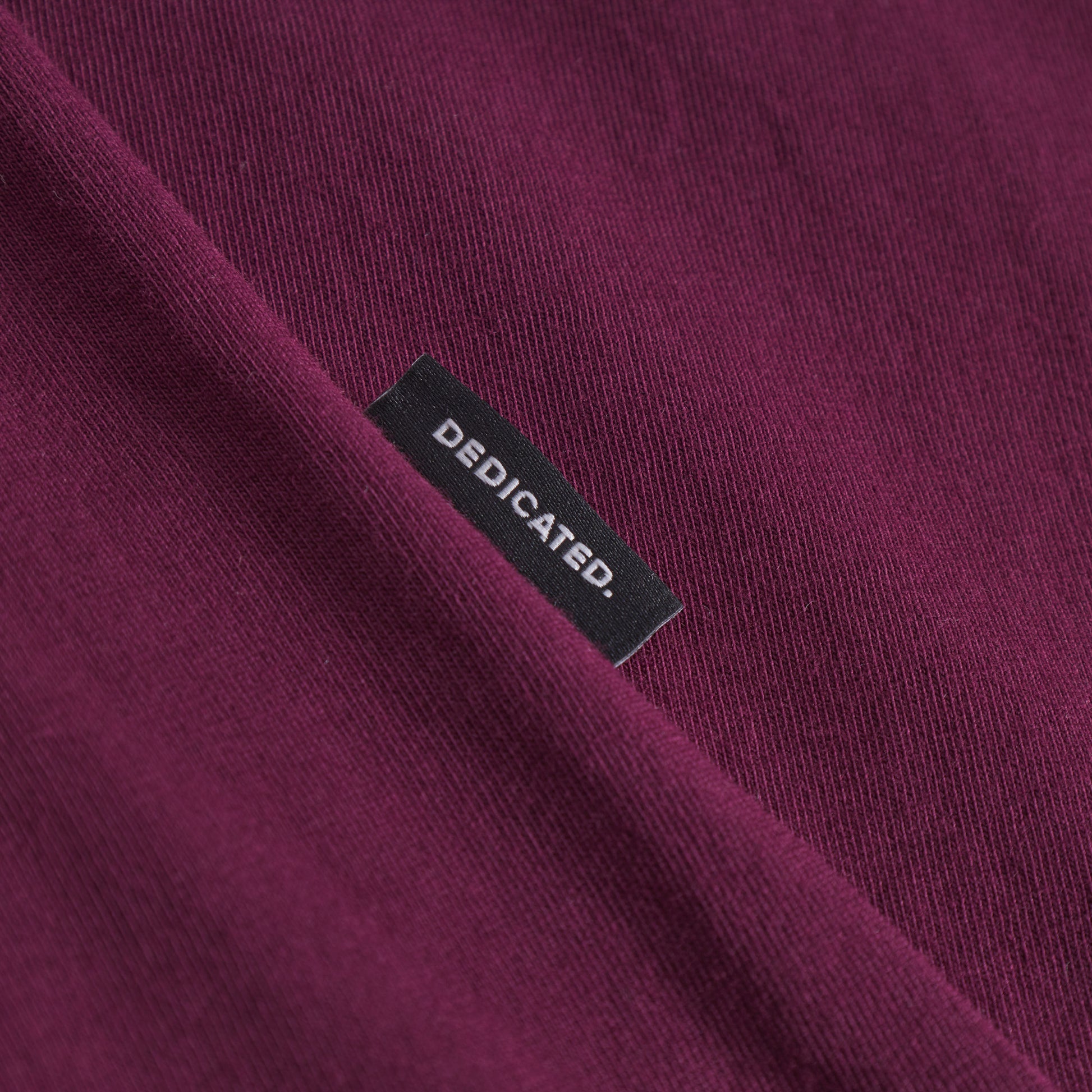 Close-up of a purple garment with a 'Dedicated' label.