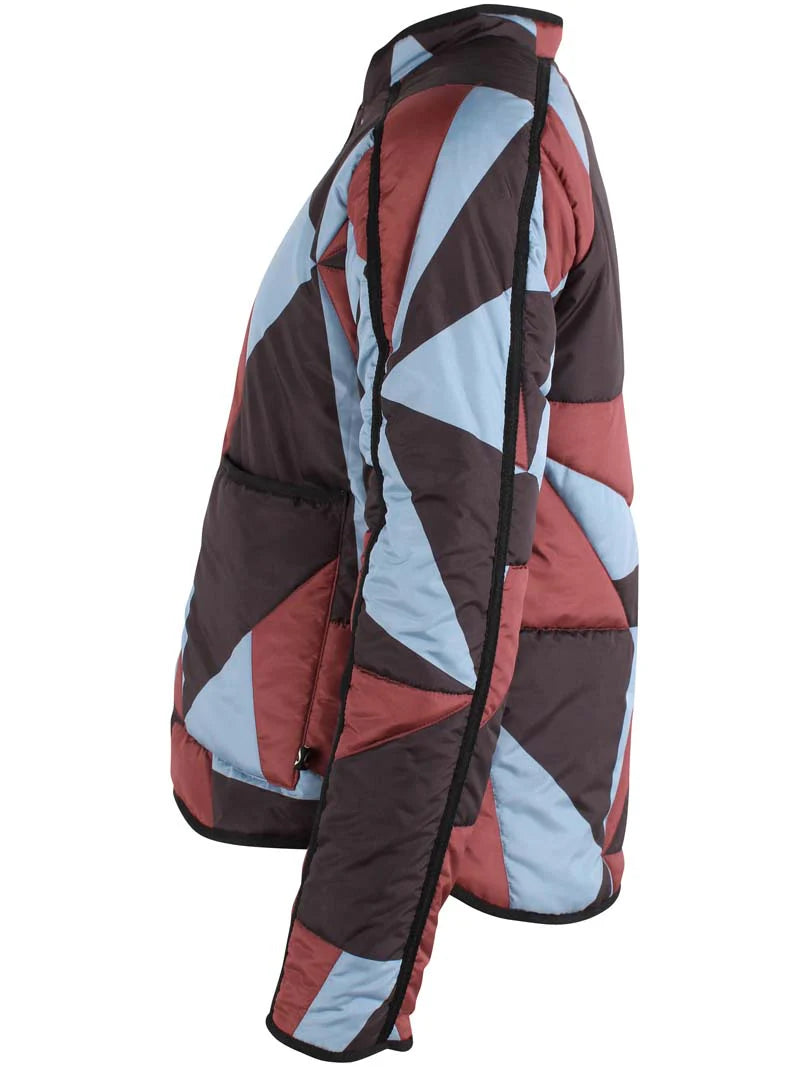 Woman wearing a thermal jacket from Danefae, featuring a geometric pattern in ice blue, wine red and black, and green beanie on a white background