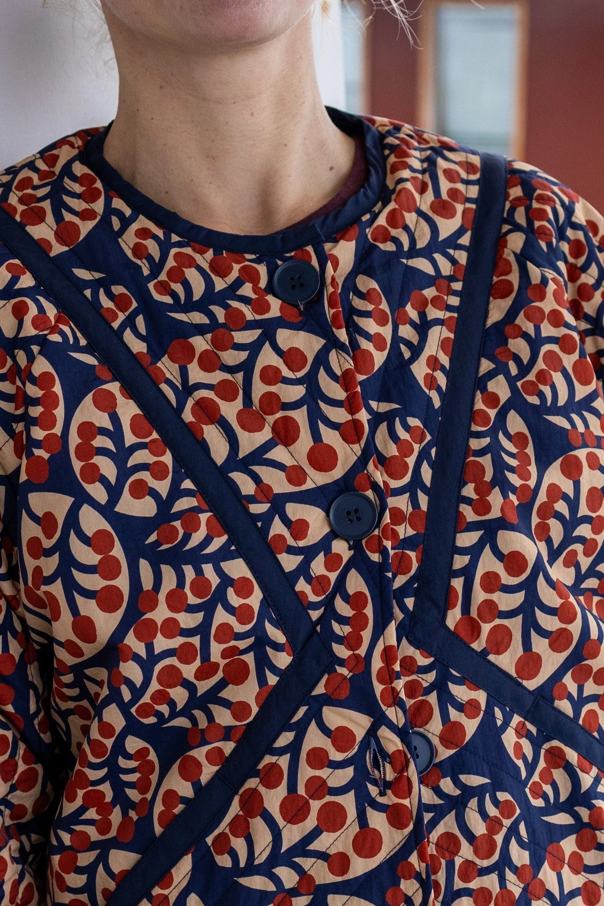 Woman wearing a patterned quilted jacket by Danefae with red and blue design