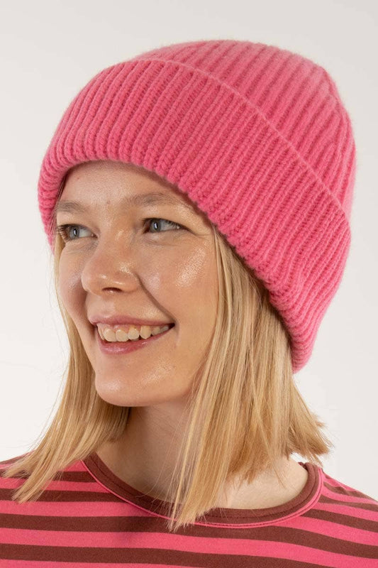 Person wearing a pink knit beanie and striped shirt against a white background