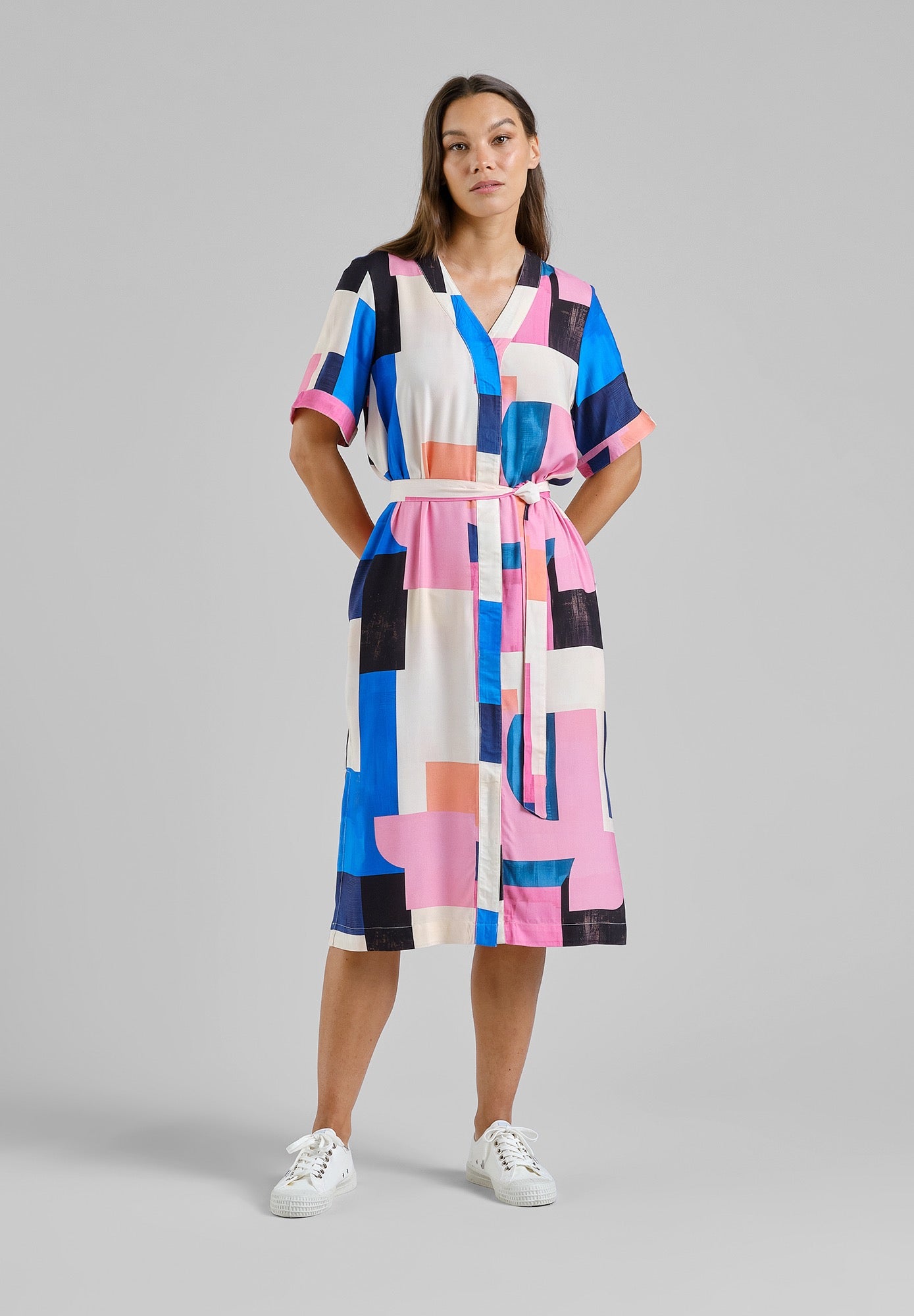 Woman wearing a colorful geometric patterned dress on a gray background