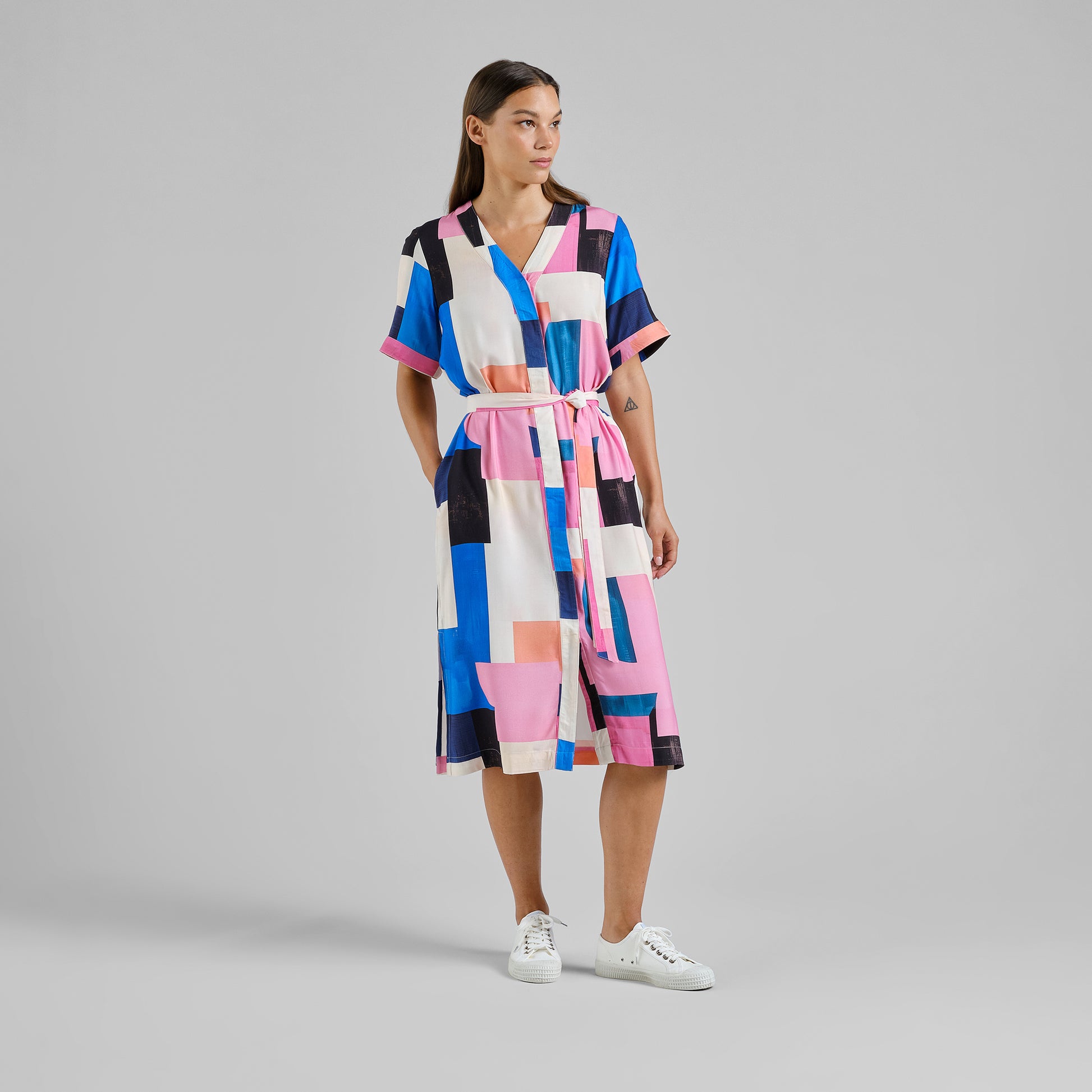 Woman wearing a colorful patchwork dress on a gray background