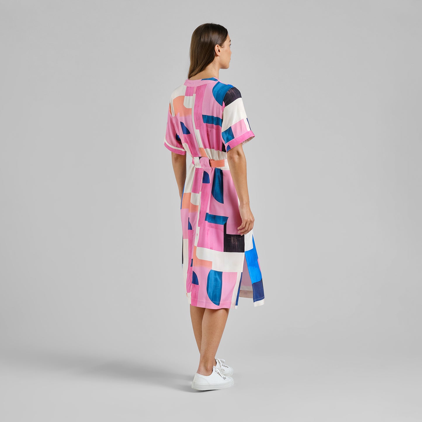 Woman wearing a colorful dress with geometric pattern on a gray background