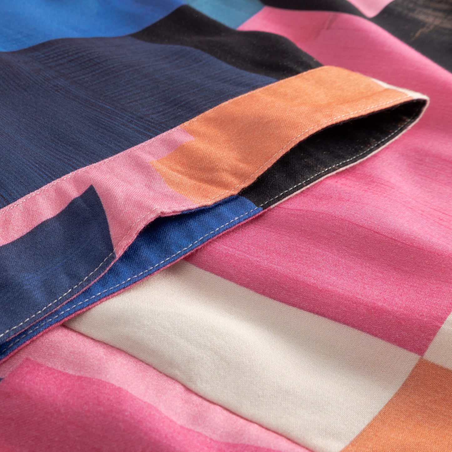 Close-up of colorful fabric with pink, blue, orange, and white sections.
