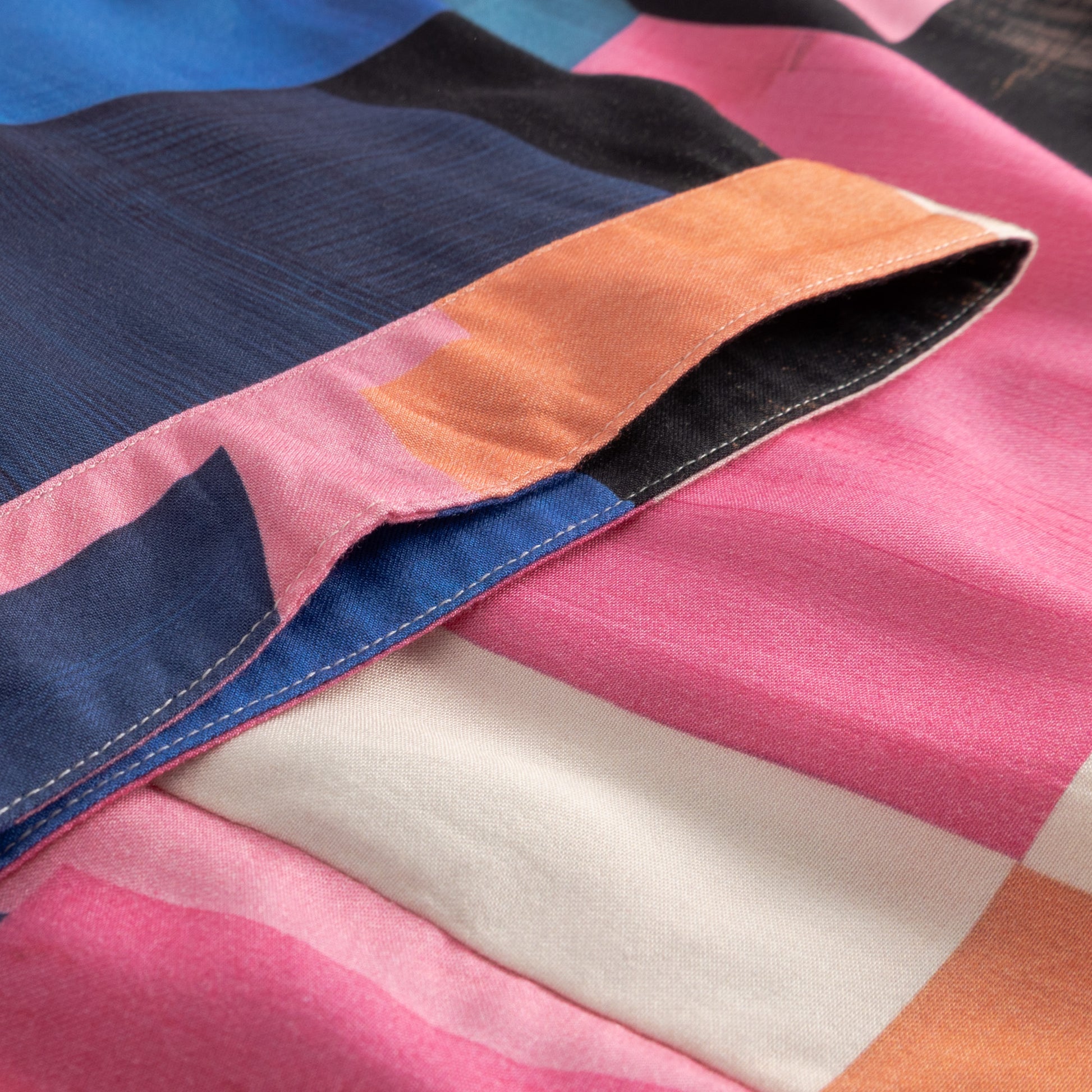 Close-up of colorful fabric with pink, blue, orange, and white sections.