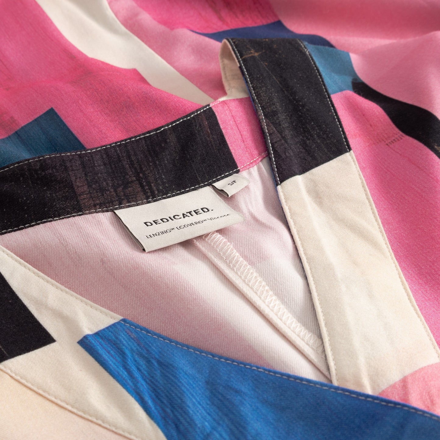 Colorful fabric with a brand label on a pink, blue, and black patterned background