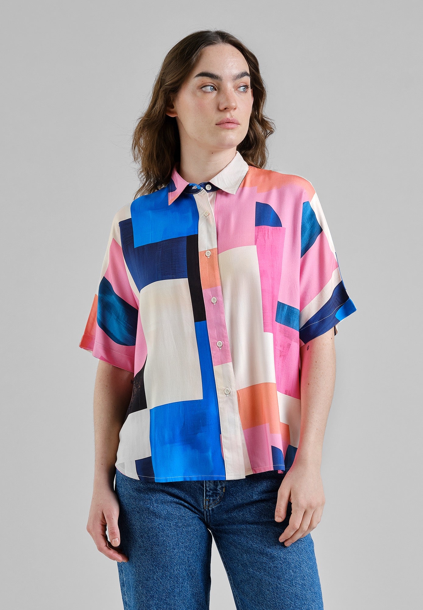 Person wearing a colorful geometric patterned shirt on a gray background