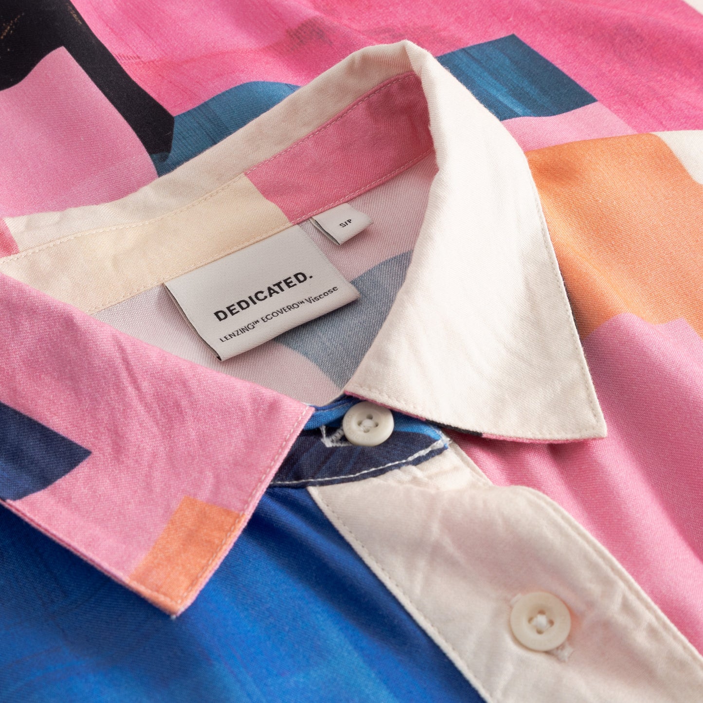 Colorful geometric-patterned shirt with a 'Dedicated' label on a matching fabric background