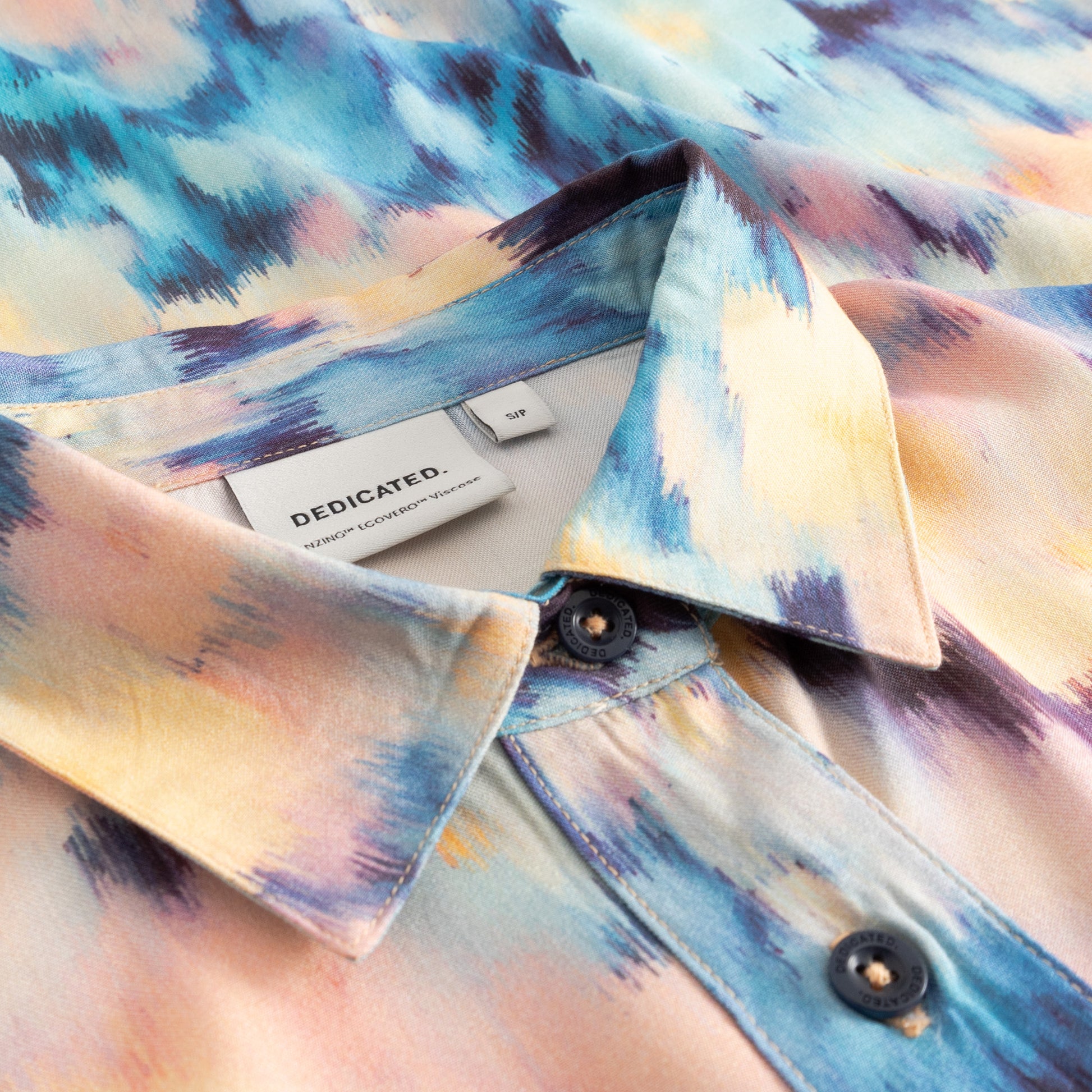 Colorful shirt with abstract pattern on a white surface, featuring a brand label.