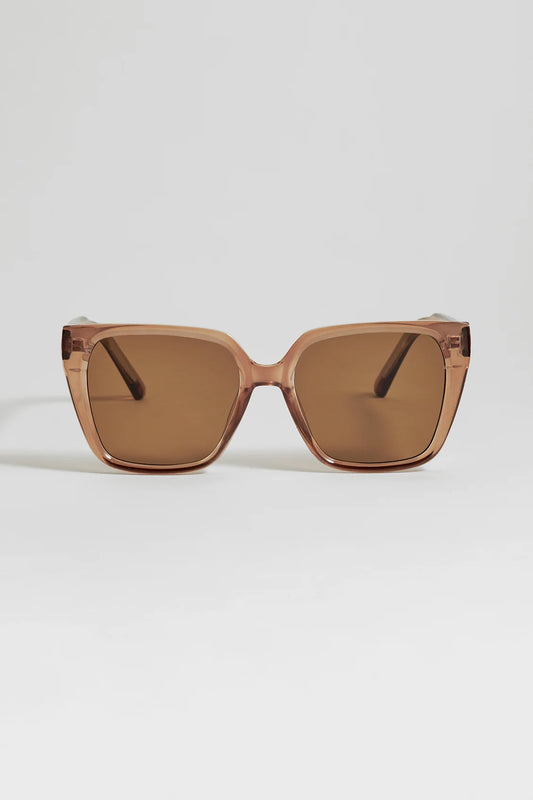 A pair of oversized square sunglasses with a translucent warm brown frame and matching brown tinted lenses, shown against a light gray background.