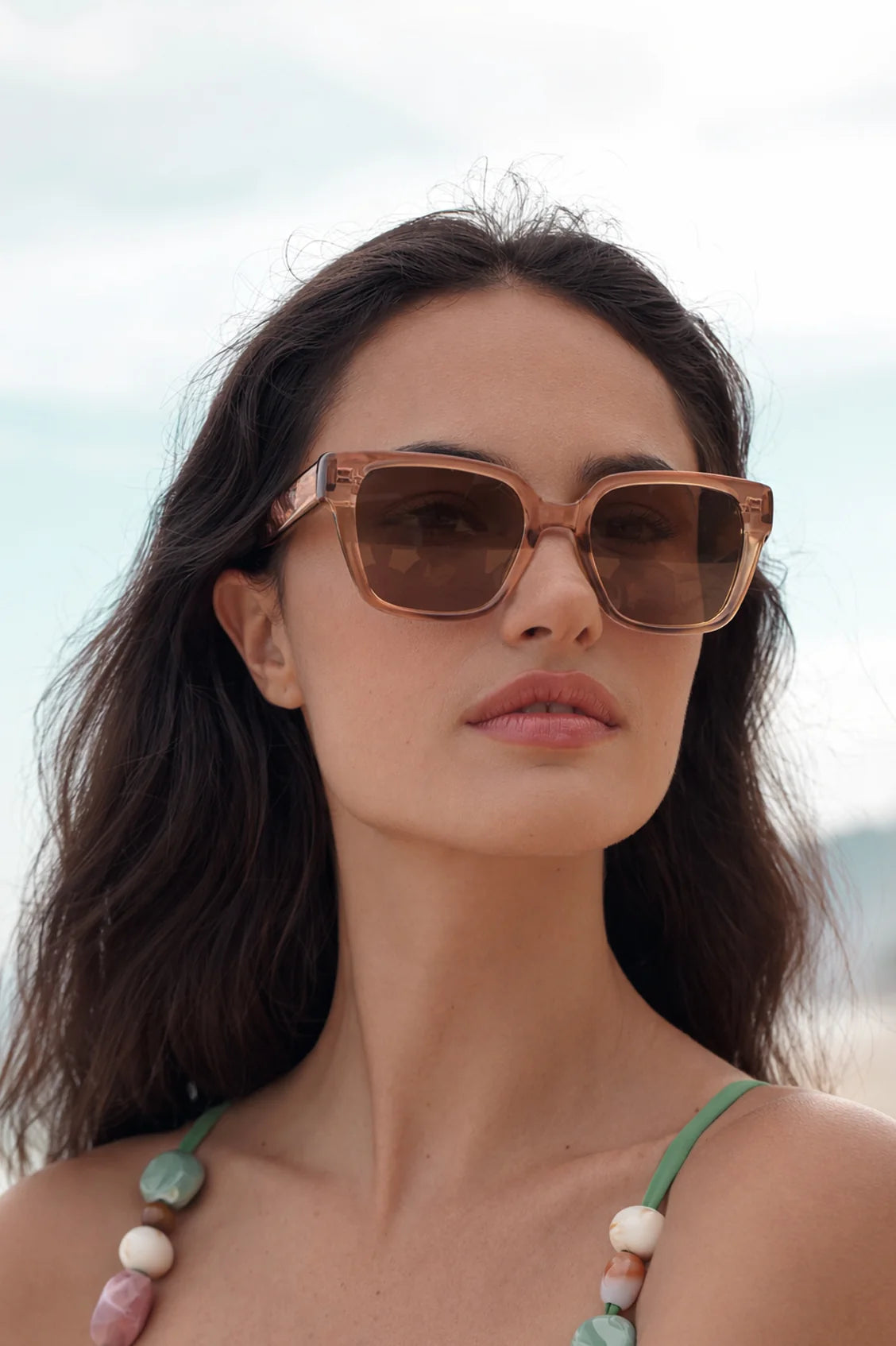 Woman wearing sunglasses with a blurred beach background