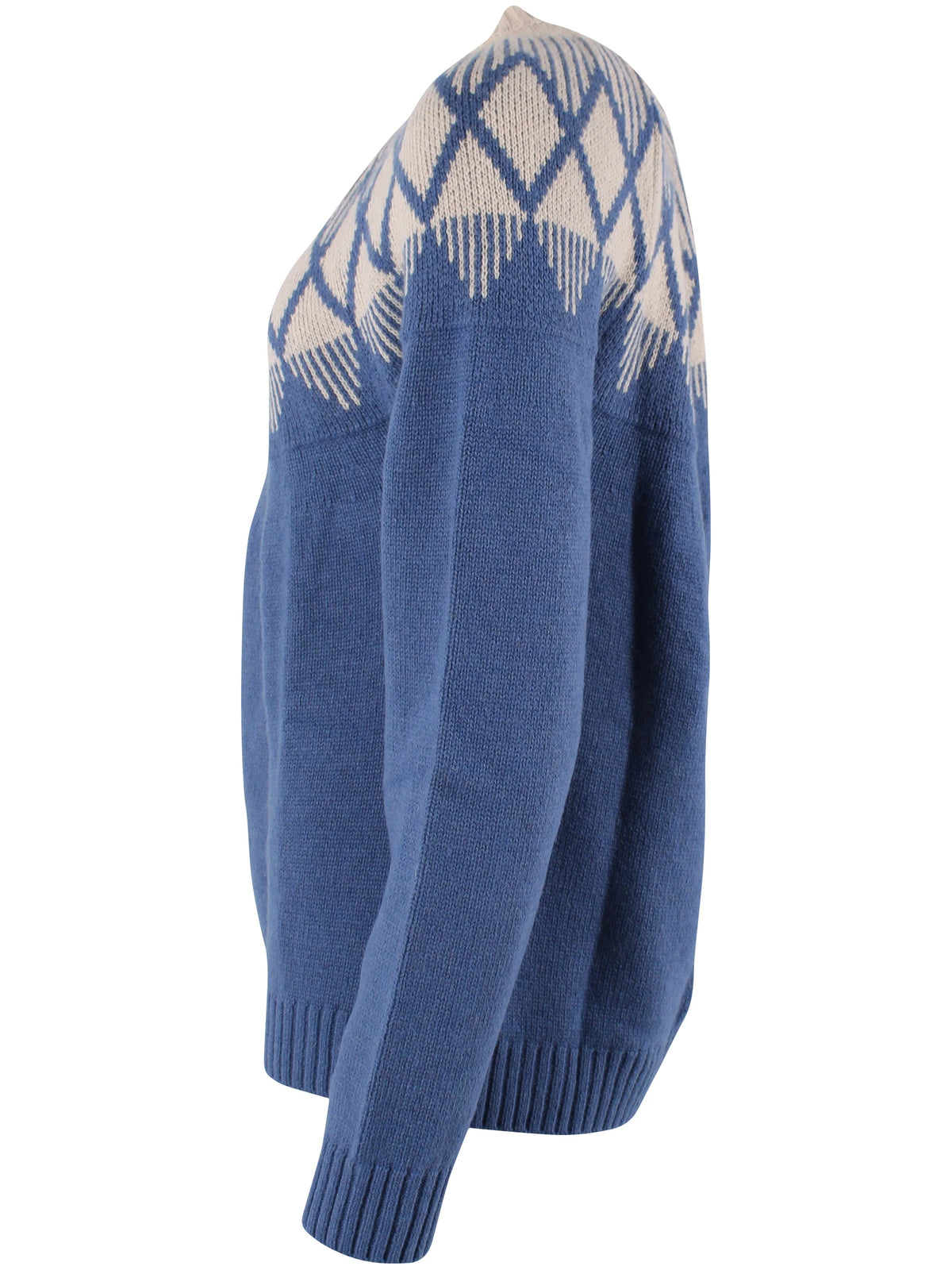 A blue knit yoke jumper by Danefae with a cream-colored geometric Fair Isle pattern across the shoulders and upper chest, shown from a side profile view on a white background.