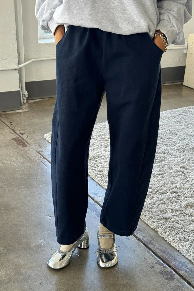 Arc Pants from Le Bon Shoppe. Barrel leg trousers made from durable cotton canvas. Featuring an elastic high waist, deep side pockets, and a slightly curved, cropped leg with a unique side panel. In a dark navy colour.
