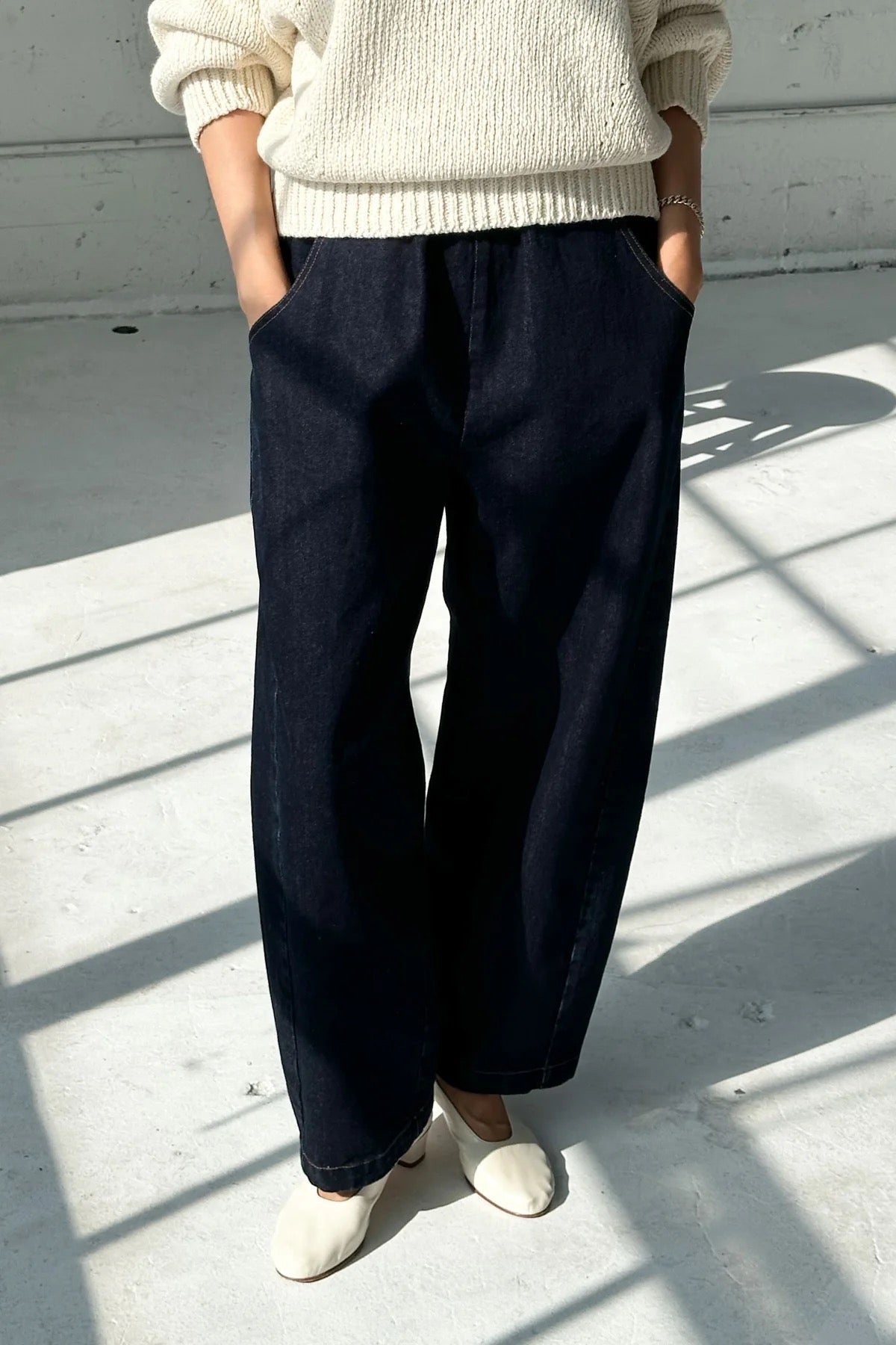 Arc Pants from Le Bon Shoppe. Barrel leg jeans with an elastic high waist and a slightly curved, cropped leg. Made from pure cotton, in a dark blue denim colour. With side pockets.