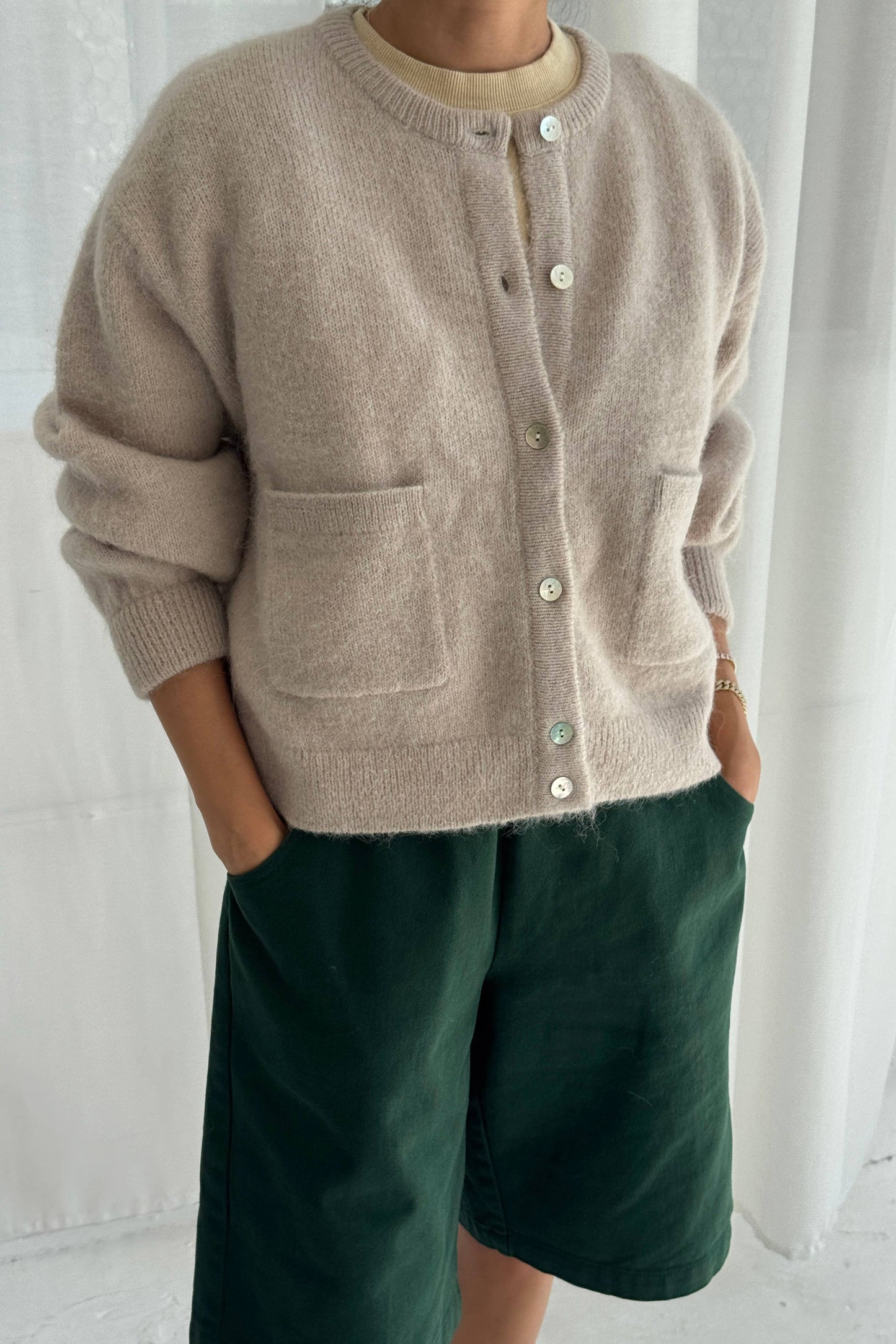 Person wearing a beige Amelie cardigan from Le Bon Shoppe and green shorts against a white background