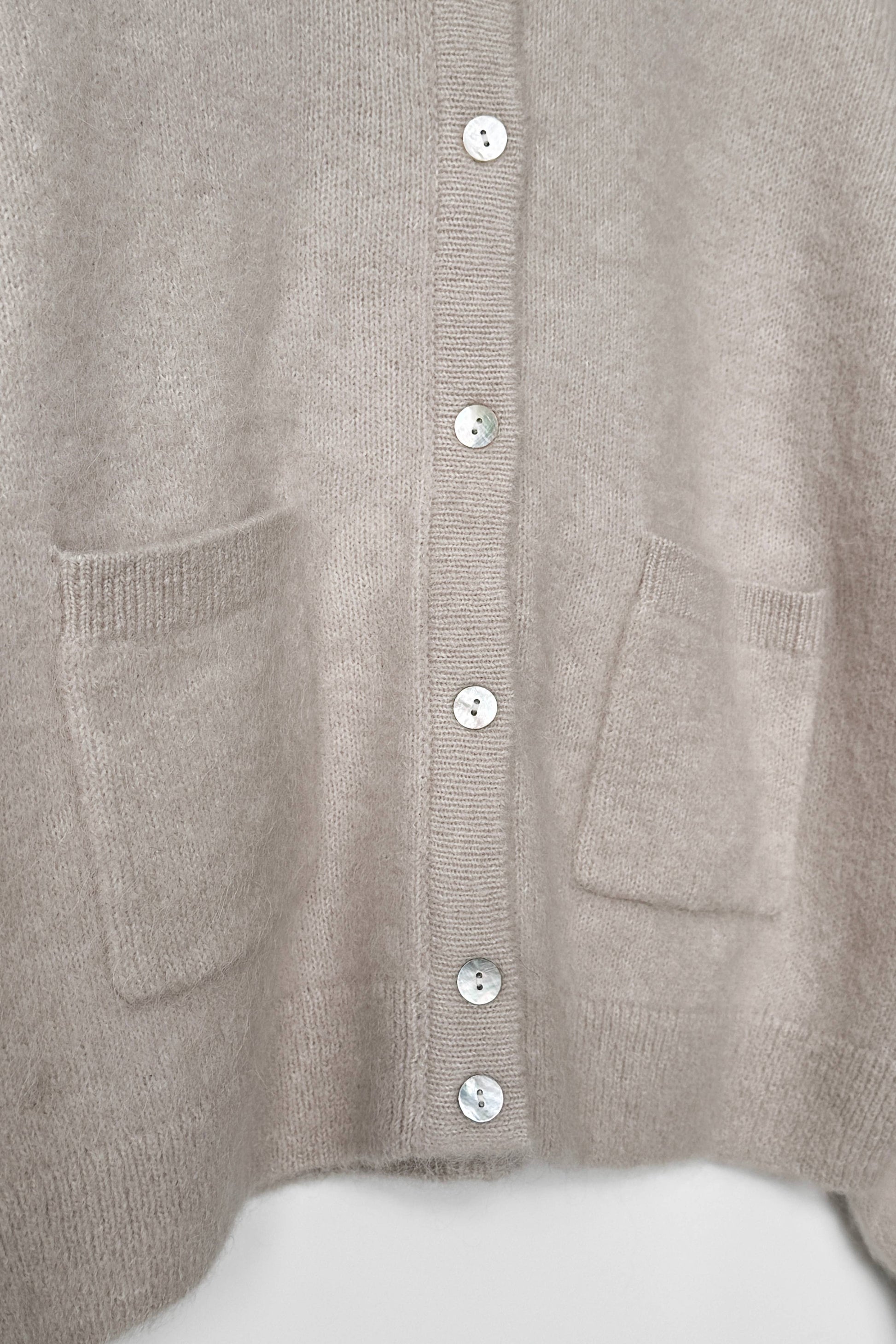 Close-up of a beige Amelie cardigan from Le Bon Shoppe with button details on a white background