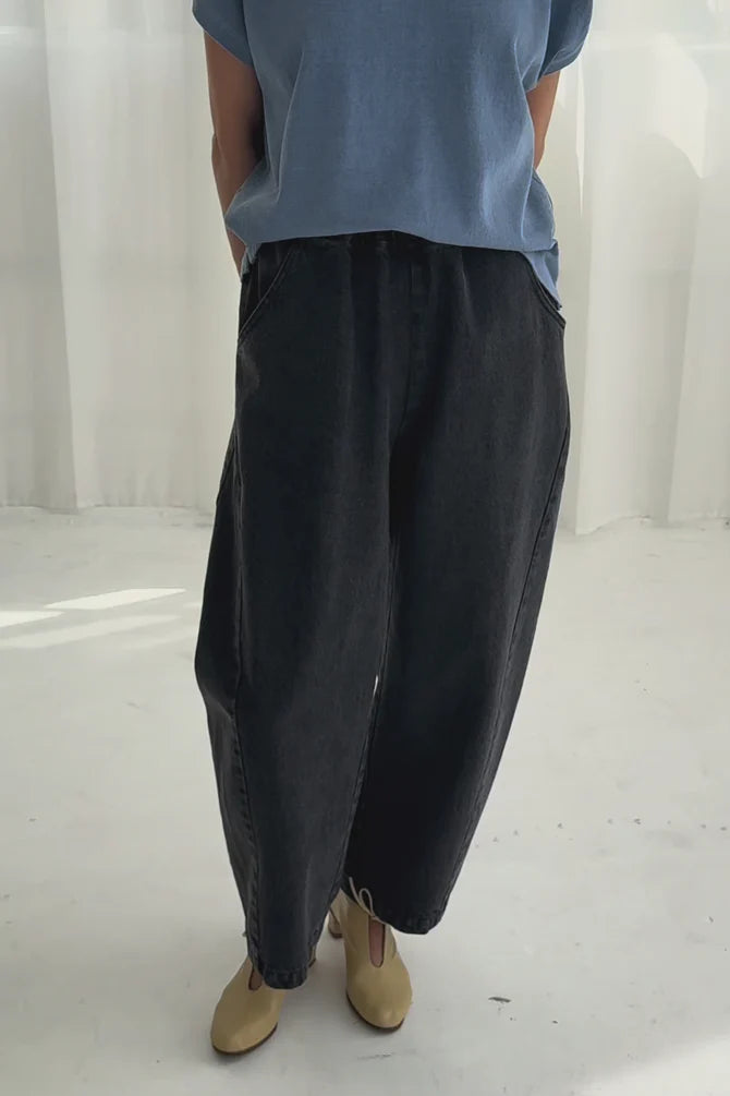 Arc Pants from Le Bon Shoppe. Barrel leg trousers made from durable cotton canvas. Featuring an elastic high waist, deep side pockets, and a slightly curved, cropped leg with a unique side panel. Washed out black denim.