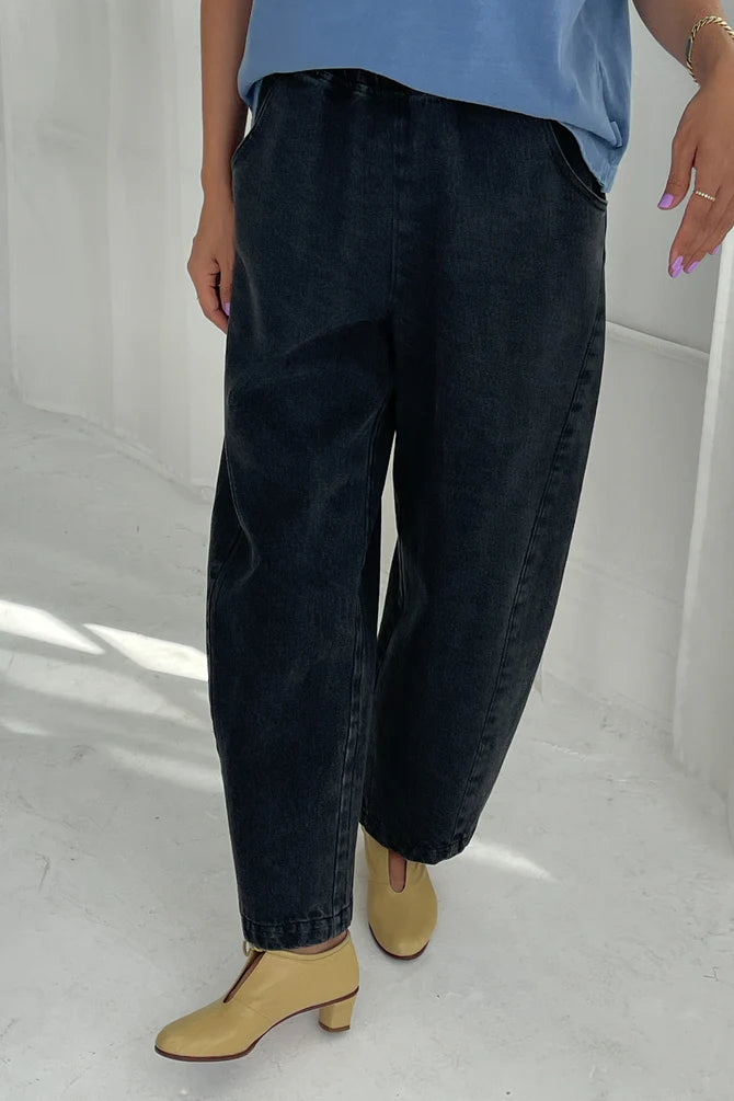 Arc Pants from Le Bon Shoppe. Barrel leg trousers made from durable cotton canvas. Featuring an elastic high waist, deep side pockets, and a slightly curved, cropped leg with a unique side panel. Washed out black denim.