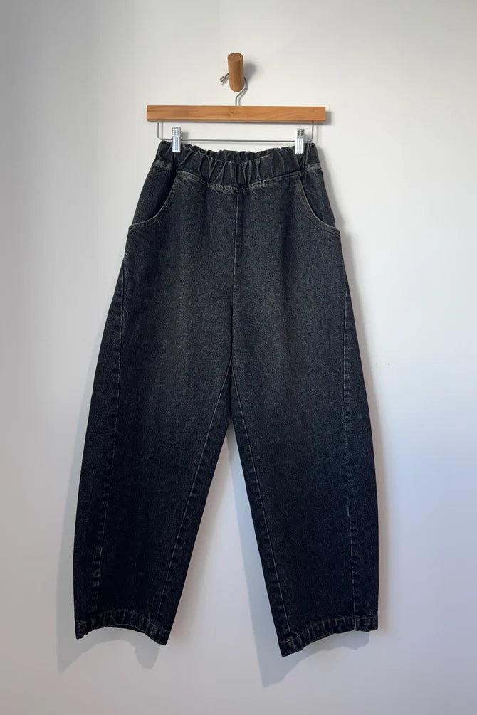 Arc Pants from Le Bon Shoppe. Barrel leg trousers made from durable cotton canvas. Featuring an elastic high waist, deep side pockets, and a slightly curved, cropped leg with a unique side panel. Washed out black denim.