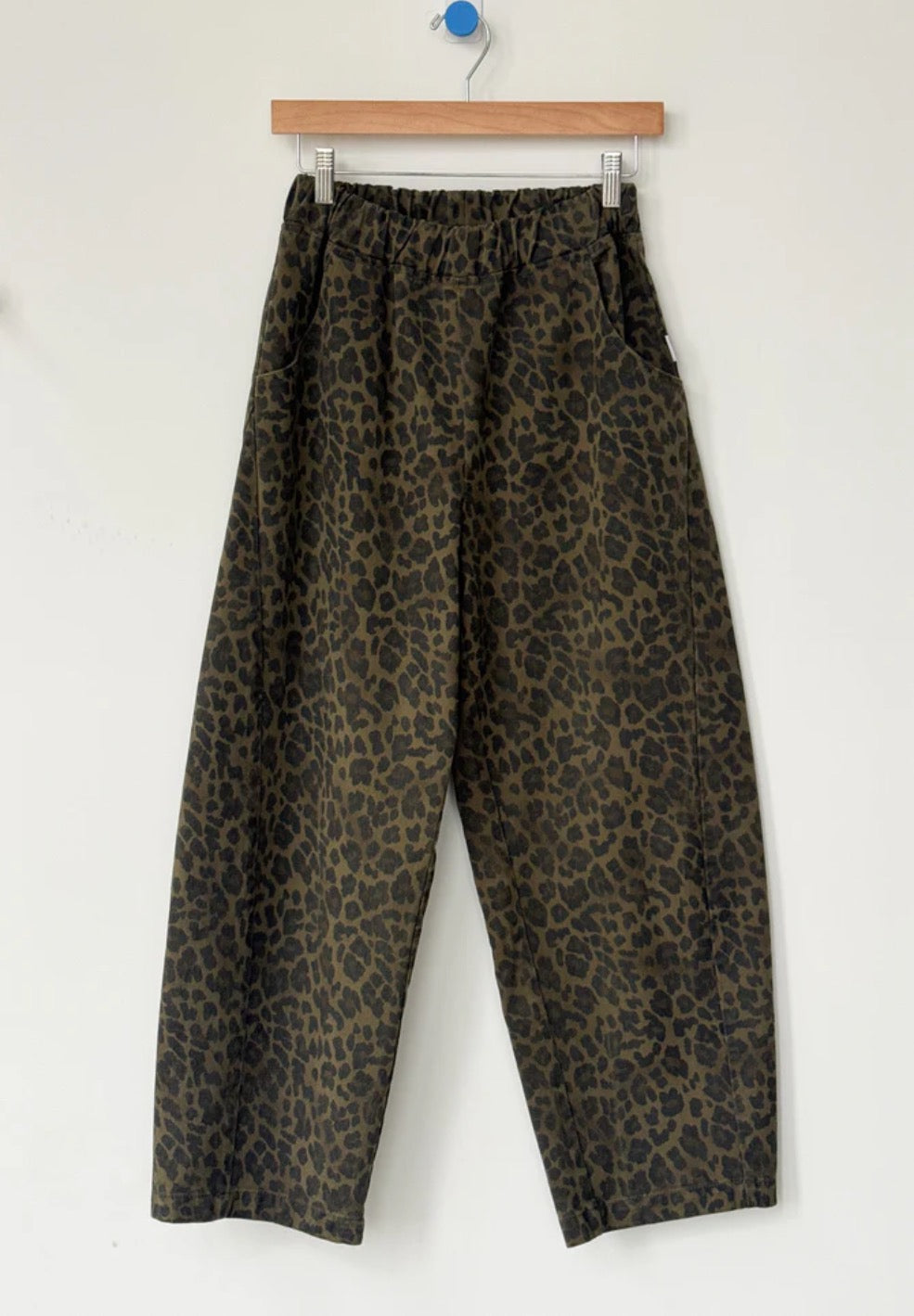 Arc Pants from Le Bon Shoppe. Barrel leg trousers made from durable cotton canvas. Featuring an elastic high waist, deep side pockets, and a slightly curved, cropped leg with a unique side panel. Leopard print on dark green background.