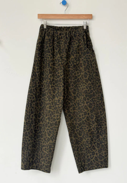 Arc Pants from Le Bon Shoppe. Barrel leg trousers made from durable cotton canvas. Featuring an elastic high waist, deep side pockets, and a slightly curved, cropped leg with a unique side panel. Leopard print on dark green background.